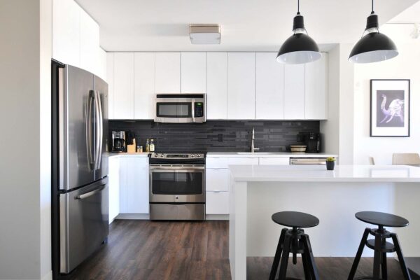 Apartment kitchen with wood style floor, white cabinets, and stainless steel appliances.