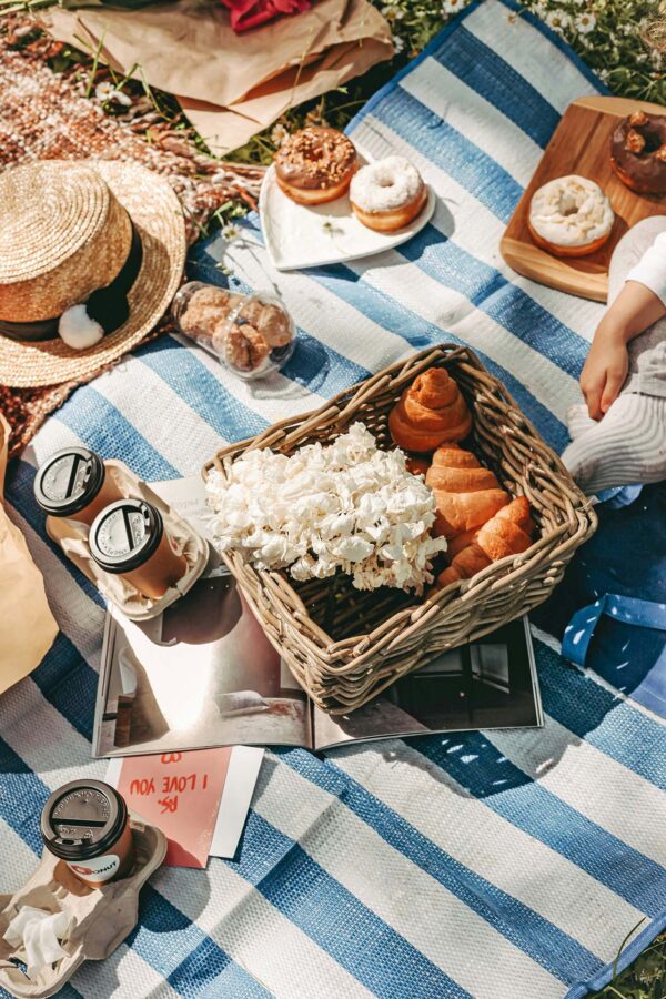 Picnic blanket with spread of food and drinks.